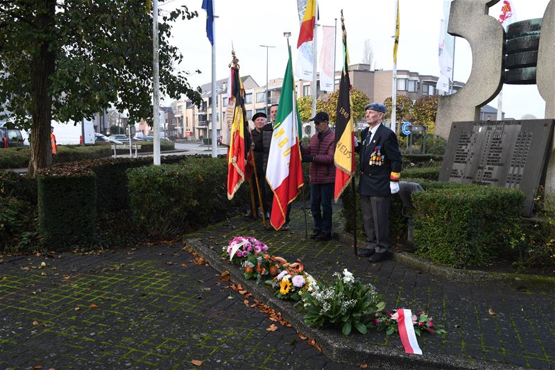 Bloemenhulde en doedelzak aan monument in Zolder