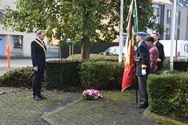 Bloemenhulde en doedelzak aan monument in Zolder