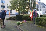 Bloemenhulde en doedelzak aan monument in Zolder